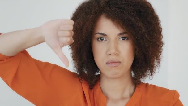 Close up angry unsatisfied African woman with curly hair displeased unhappy girl looking camera showing thumbs down rejection finger dislike negative reaction vote bad idea disapproval disappointment - Imágenes, Vídeo