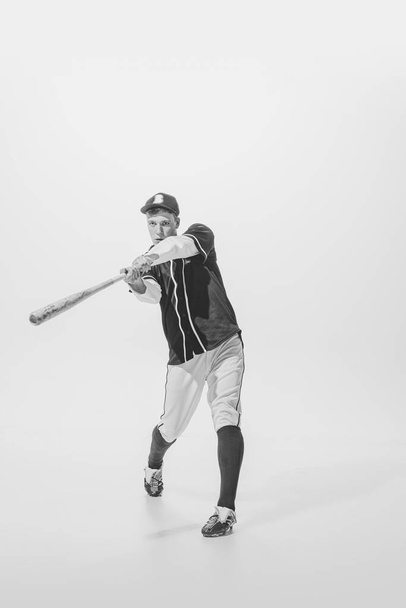 Portrait of young man, baseball player, batter ready to hit ball with bat. Black and white photography. Training activity. Concept of sport, retro style, 20s, fashion, action, college sport, youth - Photo, Image