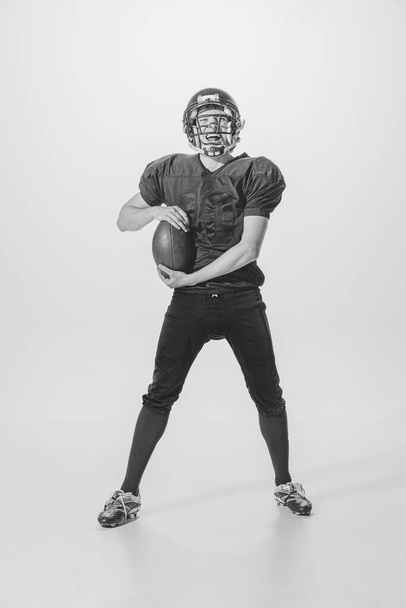 Portrait of young man, american football player posing. Black and white photography. Motivated sportsman. Winning game. Concept of sport, retro style, 20s, fashion, action, college sport, youth - Фото, зображення