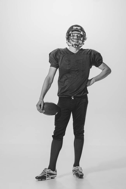 Portrait of young man, american football player posing. Black and white photography. Smiling, laughing, Winning championship. Concept of sport, retro style, 20s, fashion, action, college sport, youth - Foto, afbeelding