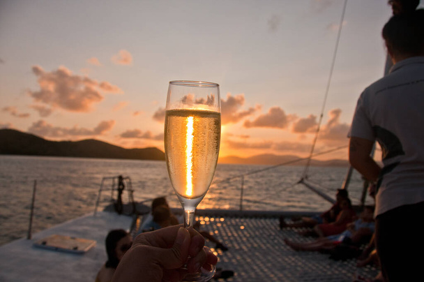 Bubby sparkling champagne flute glass with Sunset evening scene while sailing in the Pacific Ocean in Queensland Australia - Photo, image