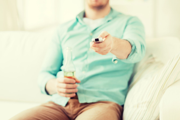 man with beer and remote control at home - Foto, Bild