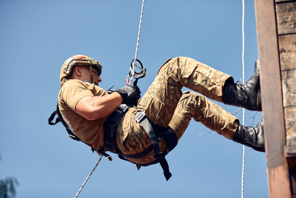 Soldado militar trepando red durante carrera de obstáculos en campo de entrenamiento
. - Foto, Imagen