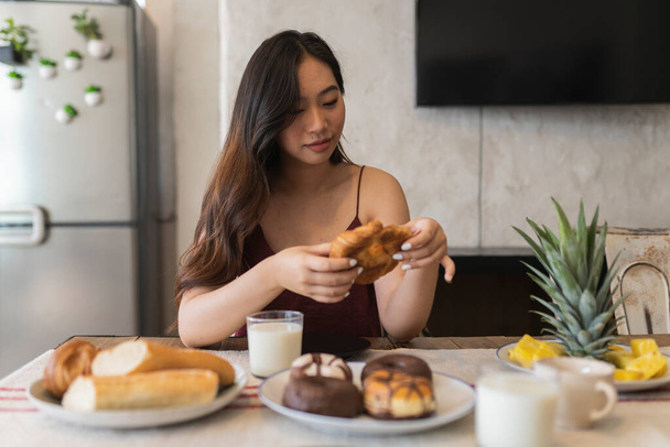 pretty asian woman having croissant breakfast at home - Foto, immagini