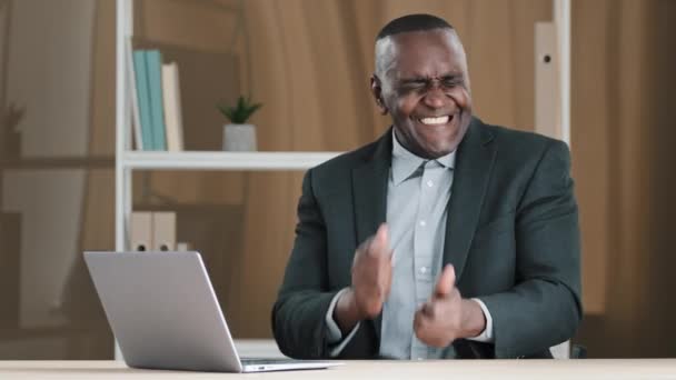 African old 50s happy silly businessman funny joyful carefree boss middle-aged man sitting desk in office dancing celebrating good news pretend playing drums drummer having fun to music singing song - Felvétel, videó