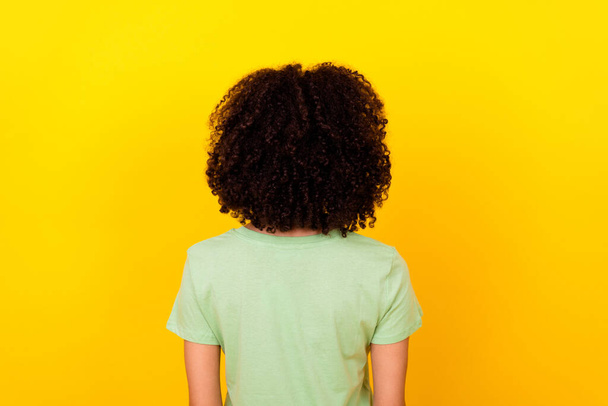 Photo of charming curly lady wear green t-shirt standing back showing hairdo isolated yellow color background. - Foto, immagini