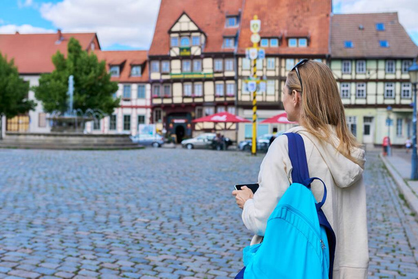 Woman tourist taking photo in an old european city, in front of historical building. Female traveling through Germany using smartphone to take photo. Tourism, history, architecture concept - Фото, изображение