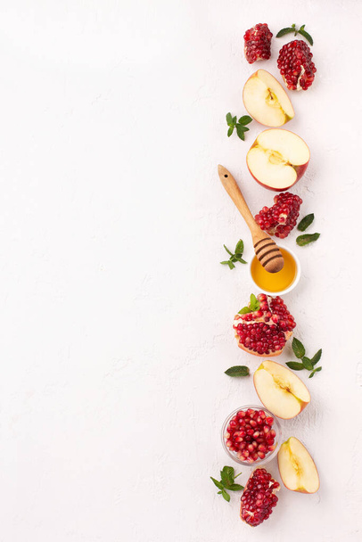Rosh Hashanah, Jewish New Year Autumn Holiday Concept. Apples, Honey, Pomegranate, Traditional Products for Celebration on White Stone Background. - Photo, Image