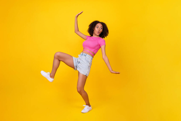 Full body portrait of impressed pretty girl sneaky walking pouted lips look empty space isolated on yellow color background. - Foto, Bild