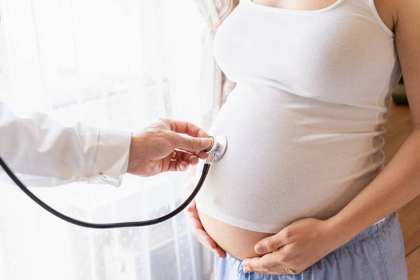 Terhes orvos kórház. Orvosi rendelő terhességi tanácsadónak. Az orvos megvizsgálja a terhes nőt, aki sztetoszkópot tart a hasában. Terhesség, orvostudomány egészségügyi koncepció - Fotó, kép