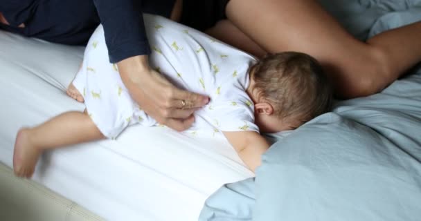 Baby descending from bed, infant getting out of bed with mother help and supervision. Child learning through effort and practice - Materiał filmowy, wideo
