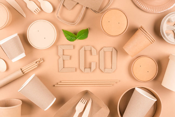 Sustainable paper packaging for food industry - paper utensils, cups, plates, bags and food containers over light brown background. Flat lay style. Text ECO. Food delivery service  - Photo, image
