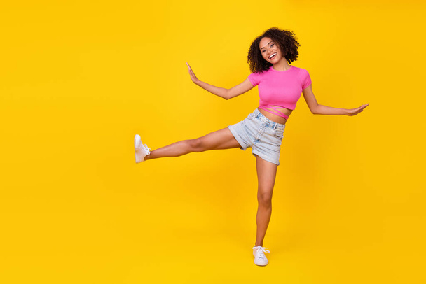 Full size portrait of carefree crazy person raise one leg enjoy free time dance isolated on yellow color background. - Фото, изображение
