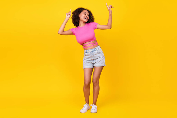 Full length portrait of cheerful nice girl point fingers enjoy dancing clubbing isolated on yellow color background. - Valokuva, kuva