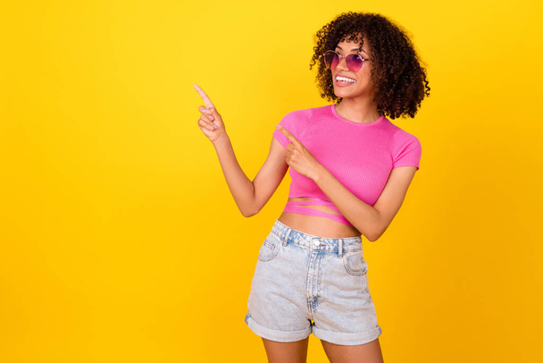Photo of cheerful pretty girl indicate fingers empty space promo isolated on yellow color background. - Foto, imagen