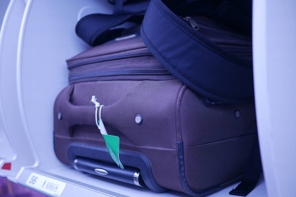 suitcase in a overhead baggage area in a Airplane cabin , - Foto, afbeelding