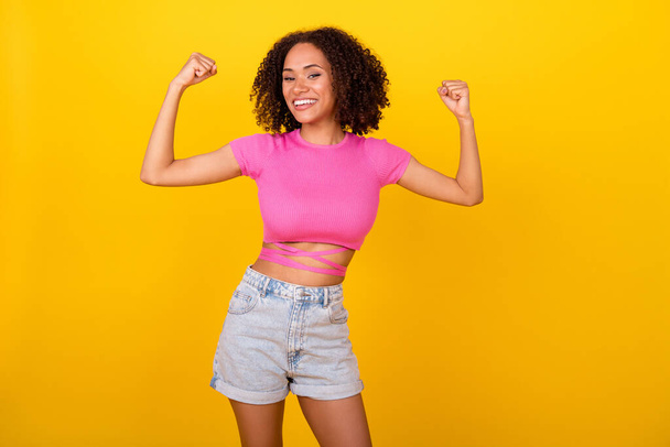 Portrait of cheerful nice person beaming smile arms show flex biceps isolated on yellow color background. - Фото, изображение
