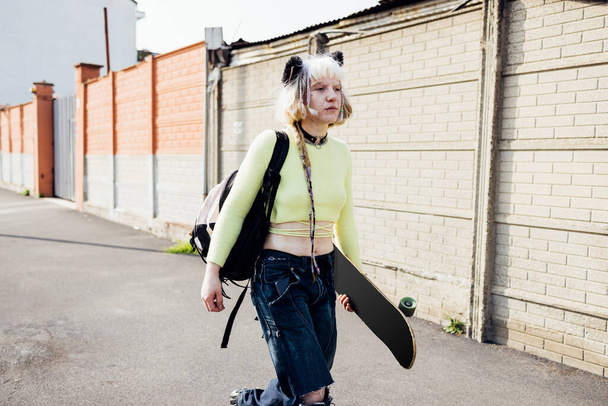 Πραγματική ομορφιά δεν μακιγιάζ επαναστάτης αντικομφορμιστής γυναίκα περπάτημα σε εξωτερικούς χώρους μεταφέρουν skateboard - Φωτογραφία, εικόνα