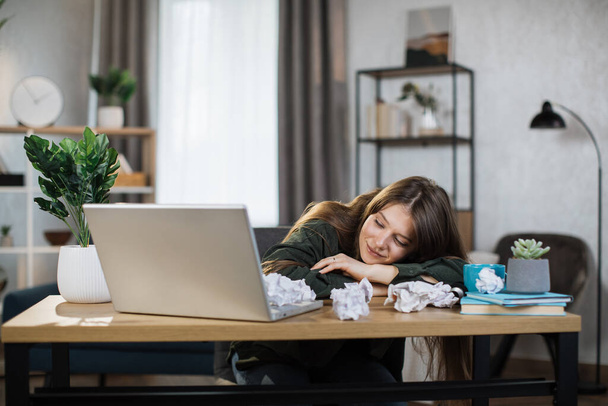 Indoor picture of smiling and tired woman sleeping on the table. Young adult business fatigue woman sleeping on table at office. Business woman tired from working overtime. - Foto, Bild