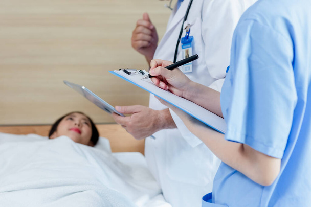 Close up hand taking notes checking up women patient symptoms on clipboard. Female doctor taking notes examining patients woman therapy for symptoms visit in hospital. - 写真・画像