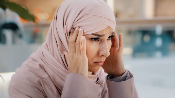 Close-up upset young woman gets bad news feels stressful anxiety frustrated muslim girl suffers from headache grabs head with hands migraine unresolved problems feeling sorrow grief divorce job loss - Foto, Imagem
