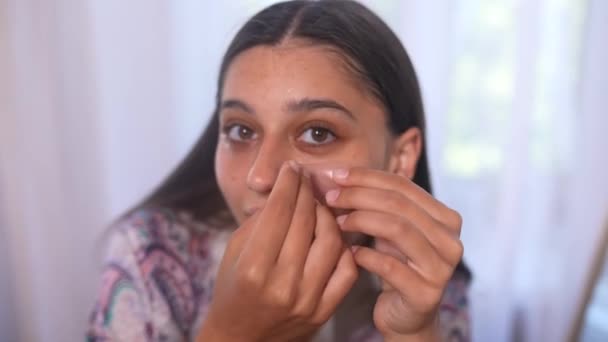Mujer guapa aplica parches transparentes de colágeno debajo de los ojos, hidrata la piel y elimina las arrugas - Metraje, vídeo
