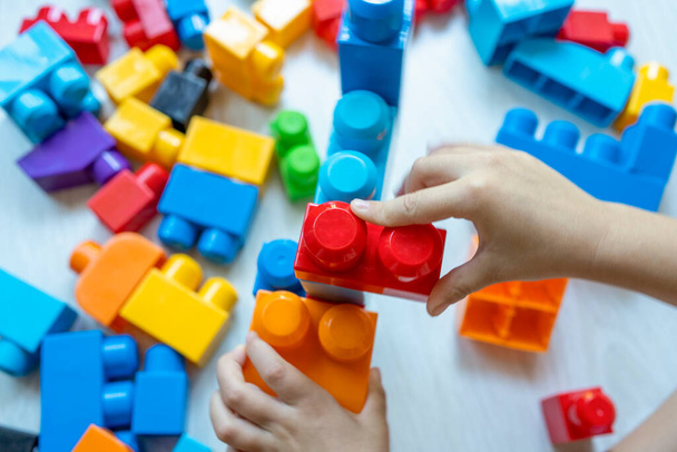 Little boy building tower of block toys sitting on floor in sunny white bedroom.  - Fotografie, Obrázek