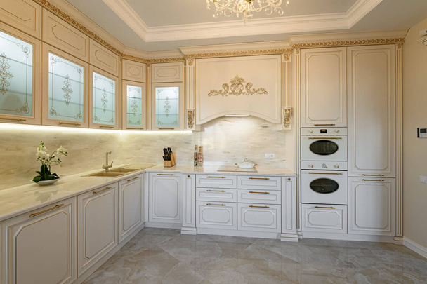Groot luxe beige en goud klassiek keukeninterieur met meubels in Provence stijl - Foto, afbeelding