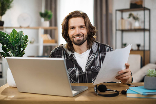 Caucasian man presenting financial report to colleagues through video call on laptop. Male freelancer sitting at workplace and talking with client. - Foto, Imagen
