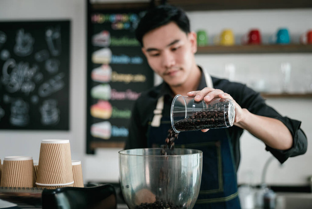 asian man bartender mixing and pouring coffee into cup from coffee machine at counter in small coffee shop business stratup concept, cinema film tone process - Foto, imagen