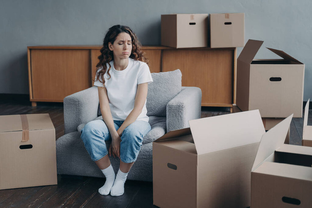Hispanic woman feels hard to live alone. Young lady is tired with boxes unpacking. Pretty girl in new apartment. Annoyed young lady has problem. Homeowner gets depression with moving. - Foto, imagen