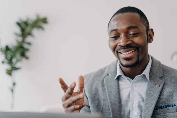 Smiling african american businessman holding a video call with customers on laptop. Optimistic black male businessperson or coach gives online consultation, advises clients. - Fotografie, Obrázek