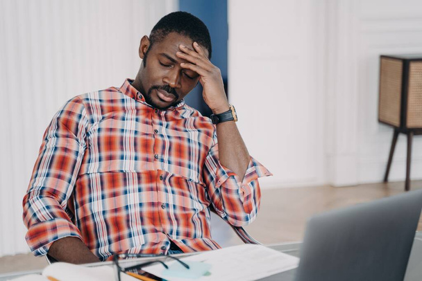 Tired african american businessman suffer from headache at workplace at laptop. Frustrated overworked black male guy touching head thinking about business problem, closed eyes. Stress at work concept - Foto, Imagem