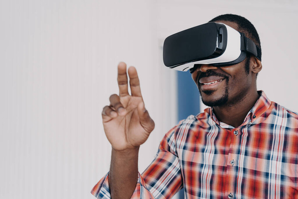 Smiling african american man using virtual reality glasses touch objects, interact with cyberspace, happy black guy in VR goggles playing online video game. Technology, entertainment. - Foto, Bild