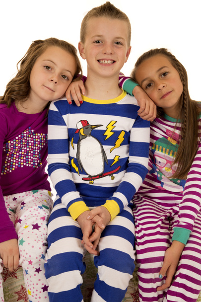 Трое детей в зимней пижаме сидят и улыбаются счастливо
 - Фото, изображение