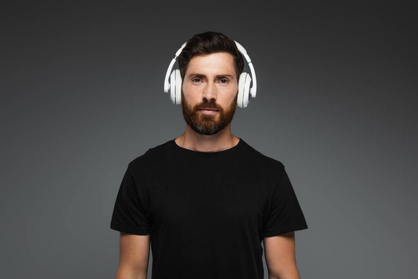 bearded man in wireless headphones listening music isolated on grey - Foto, Imagen