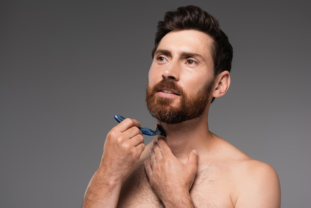 shirtless man shaving beard with safety razor isolated on grey - Foto, afbeelding