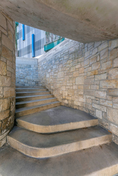 Staircase under a concrete ceiling with stone block walls at San Antonio, Texas. Staircase with concrete steps and a view of building at the background. - Foto, imagen