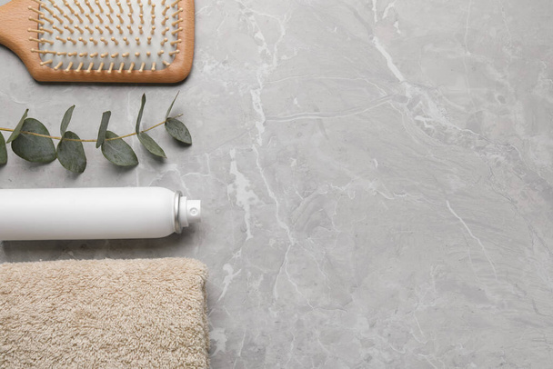 Dry shampoo spray, hairbrush, towel and eucalyptus on light marble grey table, flat lay. Space for text - Photo, Image