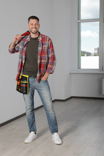 Handsome worker with wrench in empty room - Photo, image