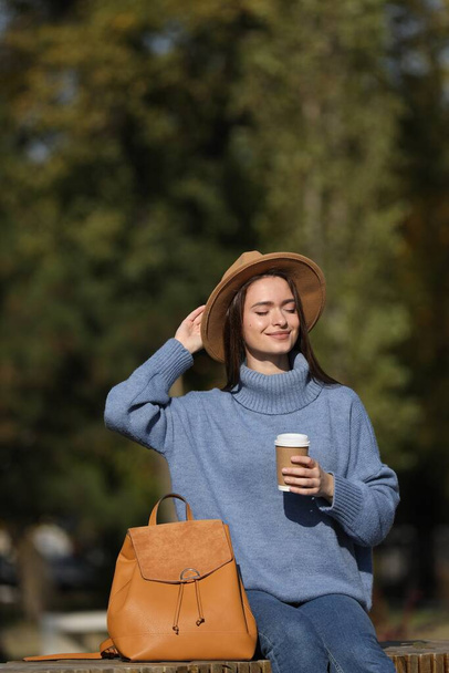 Junge Frau mit stylischem Rucksack und Heißgetränk am Herbsttag - Foto, Bild