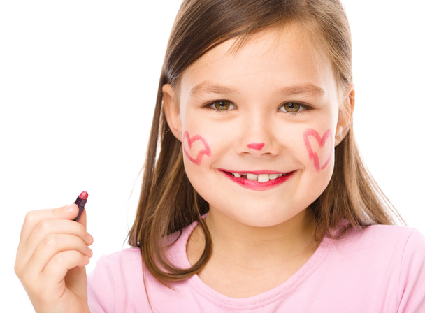 Little girl is applying lipstick on her cheek - Фото, зображення