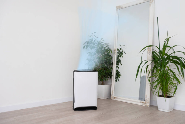 Καθαριστικό αέρα στο άνετο λευκό σαλόνι για φιλτράρισμα και καθαρισμό αφαιρώντας τη σκόνη PM2.5 HEPA και τον ιό στο σπίτι, για καθαρό αέρα και υγιή ζωή Wellness, Air Pollution Concept. - Φωτογραφία, εικόνα