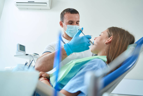 Фокусований стоматолог введення внутрішньоортопедичних анестетичних ін'єкцій підлітковому пацієнту перед лікуванням зубів
 - Фото, зображення