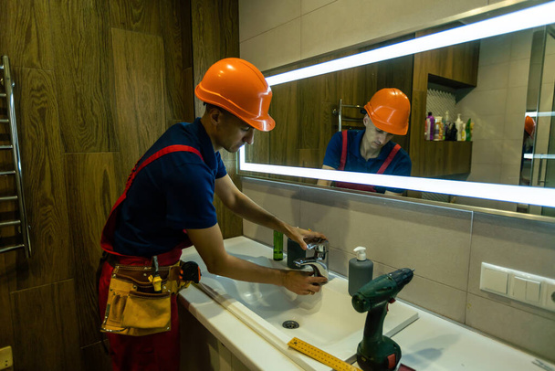 a repairman installs a faucet in a bathroom - Foto, immagini