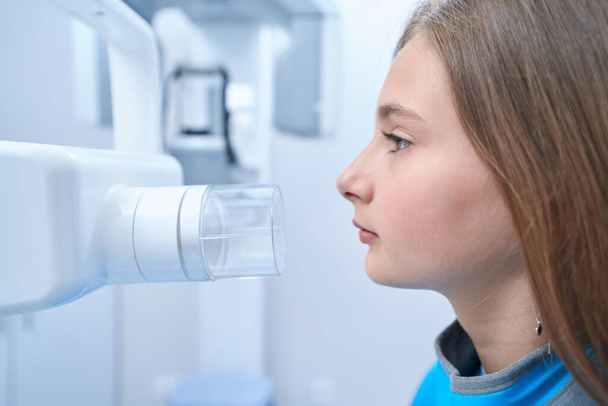 Side view of adolescent girl undergoing dental radiography procedure in medical center - Fotografie, Obrázek