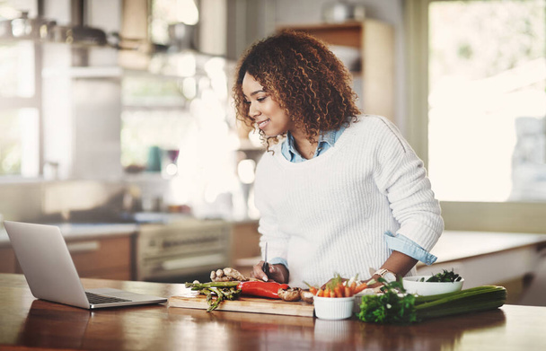 Γυναίκα μαγείρεμα νέα συνταγή από το διαδίκτυο προετοιμασία για χορτοφάγους δείπνο, μεσημεριανό γεύμα ή σνακ σε μια κουζίνα στο σπίτι. Ένα φαγητό ή μαγειρική φοιτητής δοκιμάζοντας ένα online λαχανικό, vegan ή υγιεινό πράσινο πιάτο. - Φωτογραφία, εικόνα
