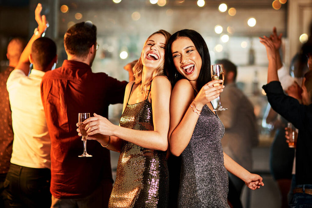 Όλα τα μάτια είναι πάνω σου. δύο χαρούμενες νεαρές γυναίκες που πίνουν ποτά ενώ χορεύουν στην πίστα ενός κλαμπ τη νύχτα - Φωτογραφία, εικόνα