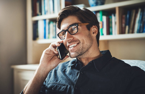 Hearing some good news for a change. a handsome young businessman making a phone call in his office at home - Foto, imagen
