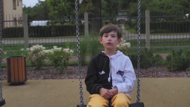 A little boy was swinging on a swing. Playground with one child. The boy rested on the swing - Video, Çekim